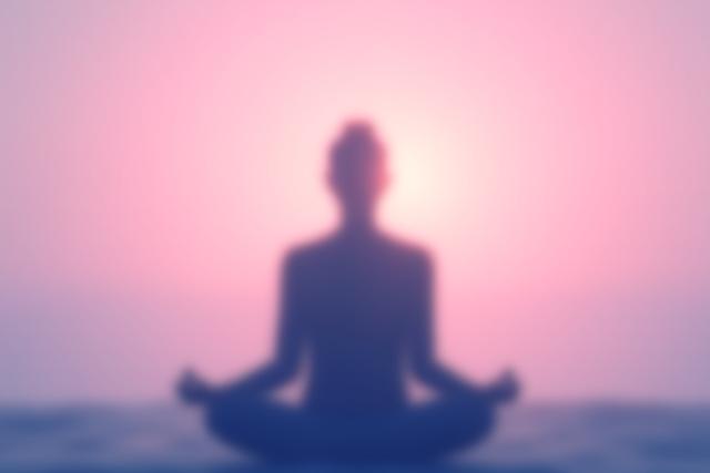 Nyugodt ember sziluettje meditál egy felkelő nap előtt, a mindfulness lényegét képviselve.